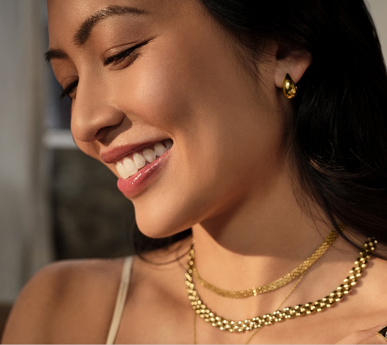 Image of a woman wearing multiple gold necklaces.