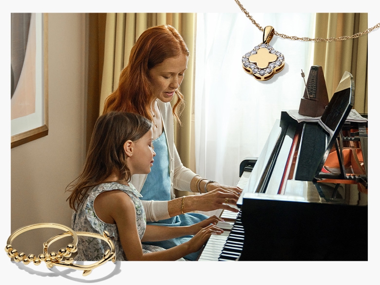 An image if a mother sitting at a piano with her daughter and showing her how to play
