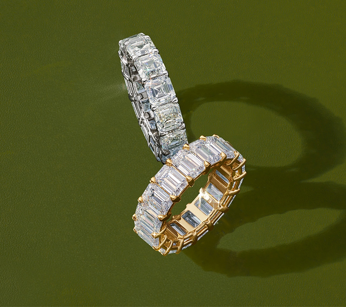 Two eternity bands, one in yellow gold with emerald cut diamonds, and one with white gold and asscher cut diamonds.