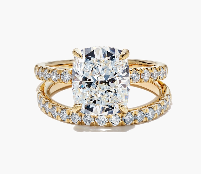 Helzberg engagement ring featuring an elongated cushion-cut center diamond with round diamond accents on a gold band, paired with a matching diamond wedding band.