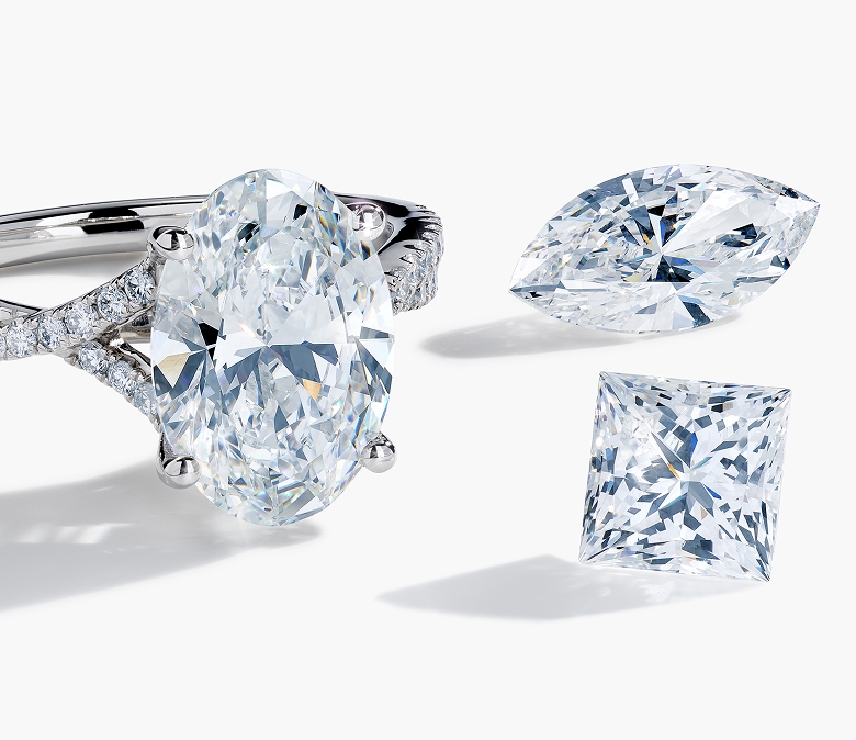 A Helzberg diamond engagement ring with two loose diamonds next to it.