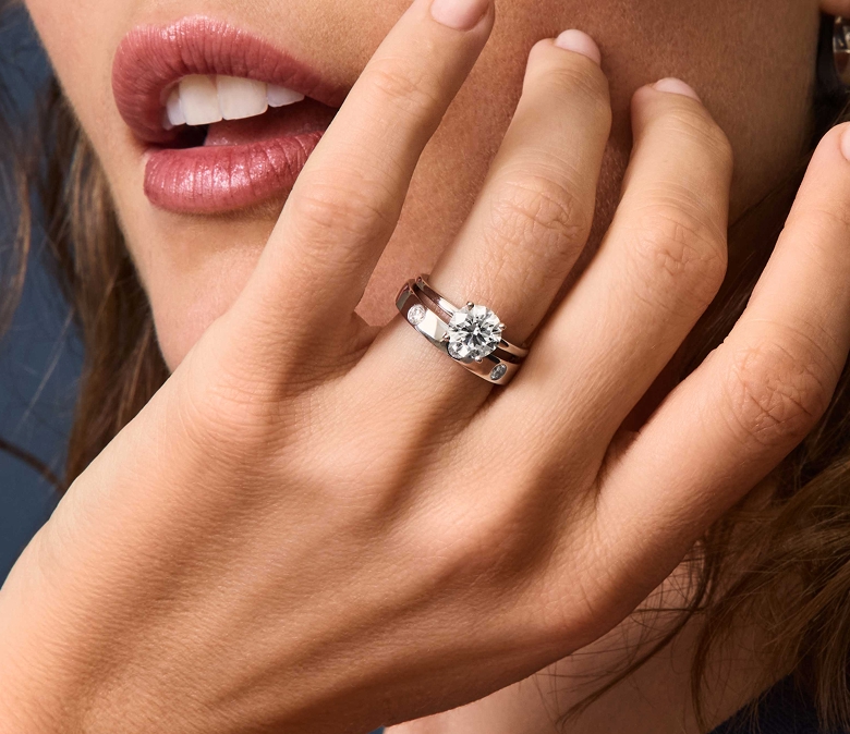 Picture of an round diamond engagement ring on hand. 