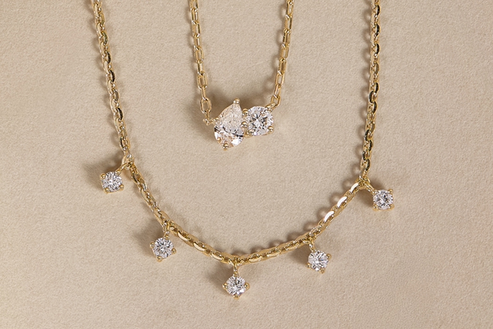 Picture of miMAGE OF TWO NECKLACES WITH LAB GROWN DIAMONDS ON THEM ans hand with wedding band on ring finger 