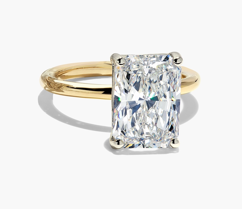 A radiant cut diamond engagement ring with a yellow gold band.