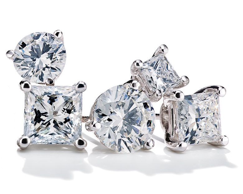 Diamond solitaire stud earrings stacked together on a white background