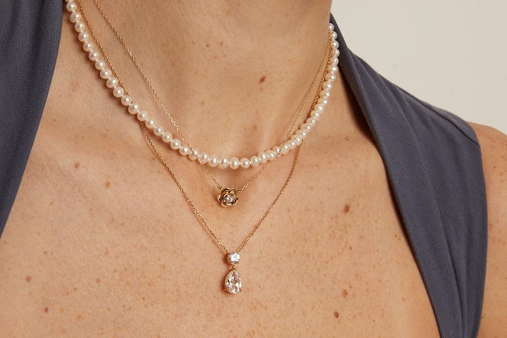 An image of a neck wearing multiple Laure by Aurate necklaces