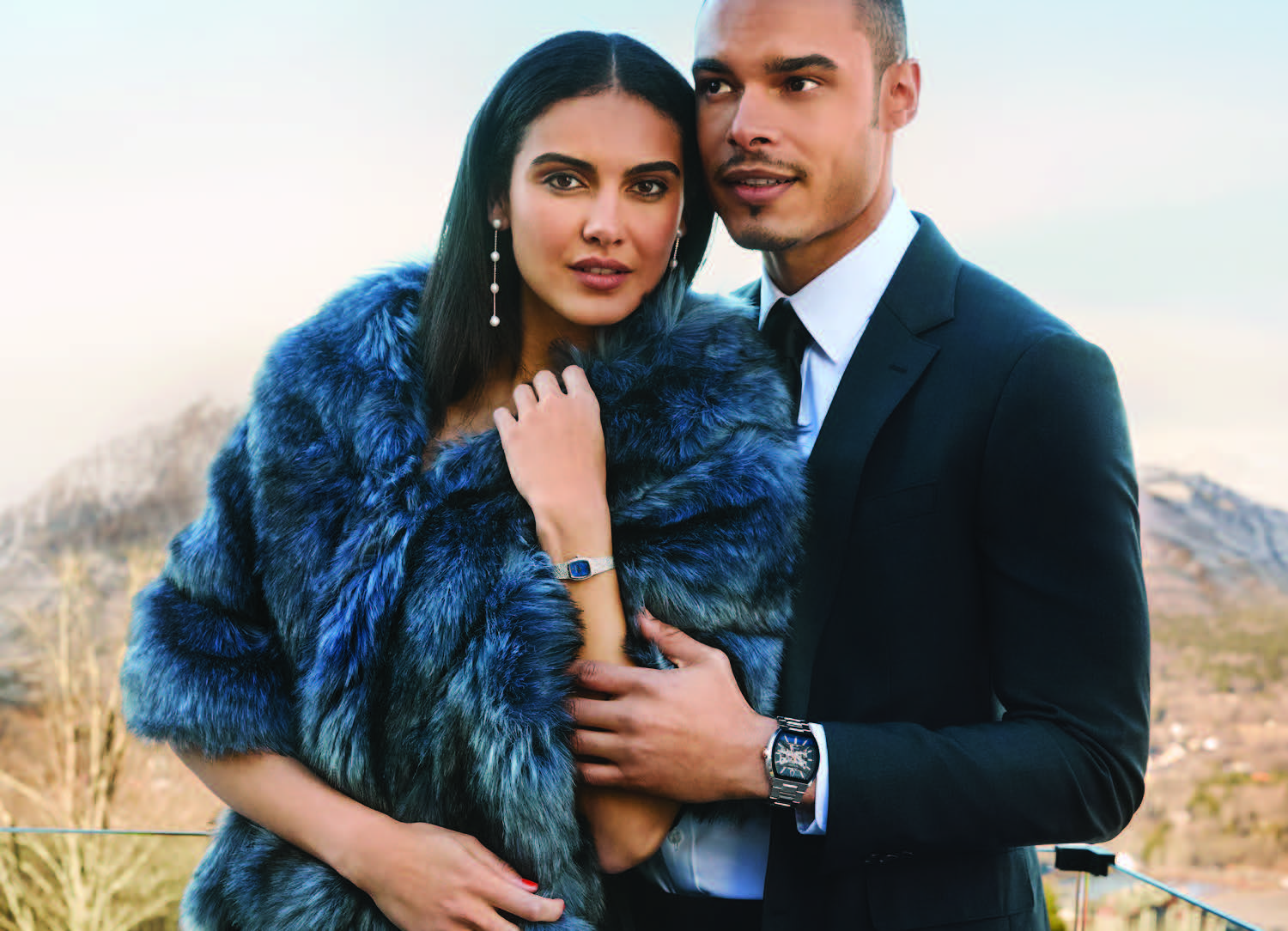 A man and woman standing together wearing summer clothing both wearing Bulova watches.