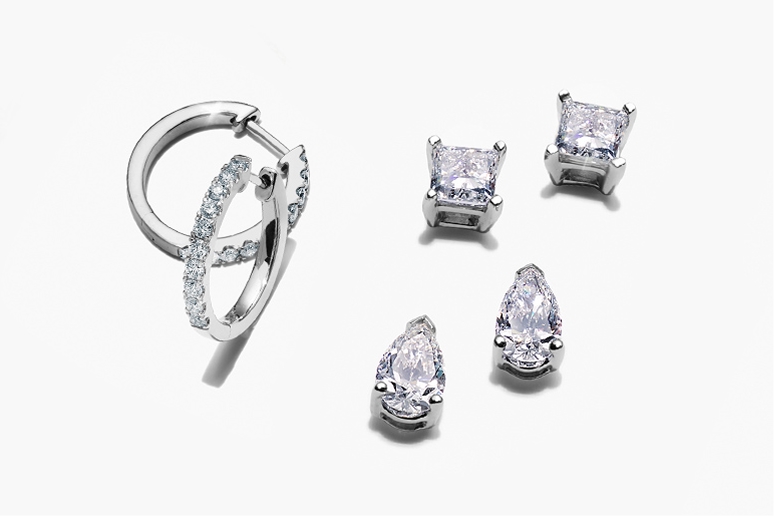 a pair of diamond white gold hoops, one pair of white gold princess cut diamond solitaire stud earrings and one pair of white gold pear shaped diamond stud earrings