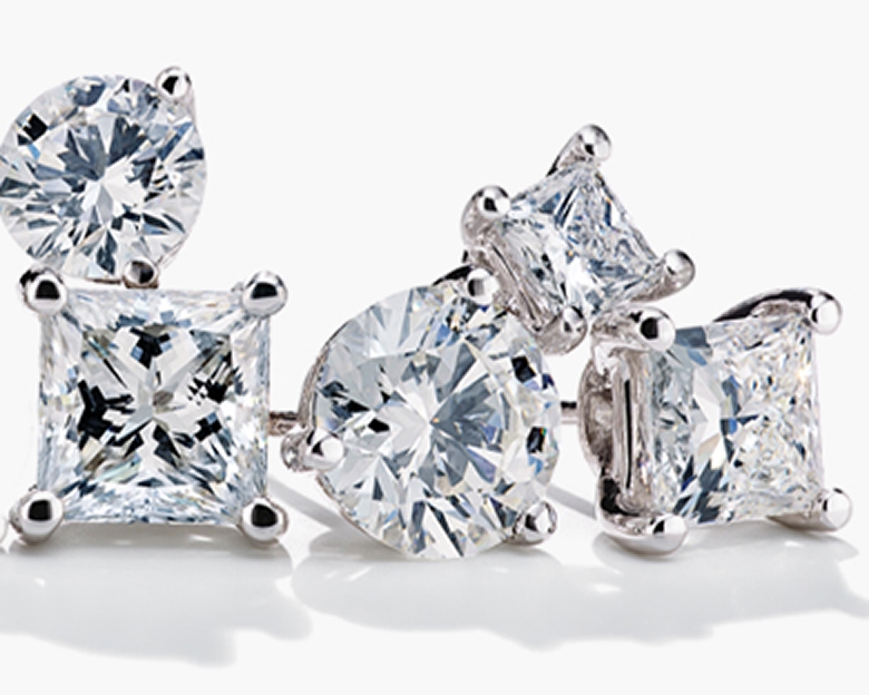 Diamond solitaire stud earrings stacked together on a white background