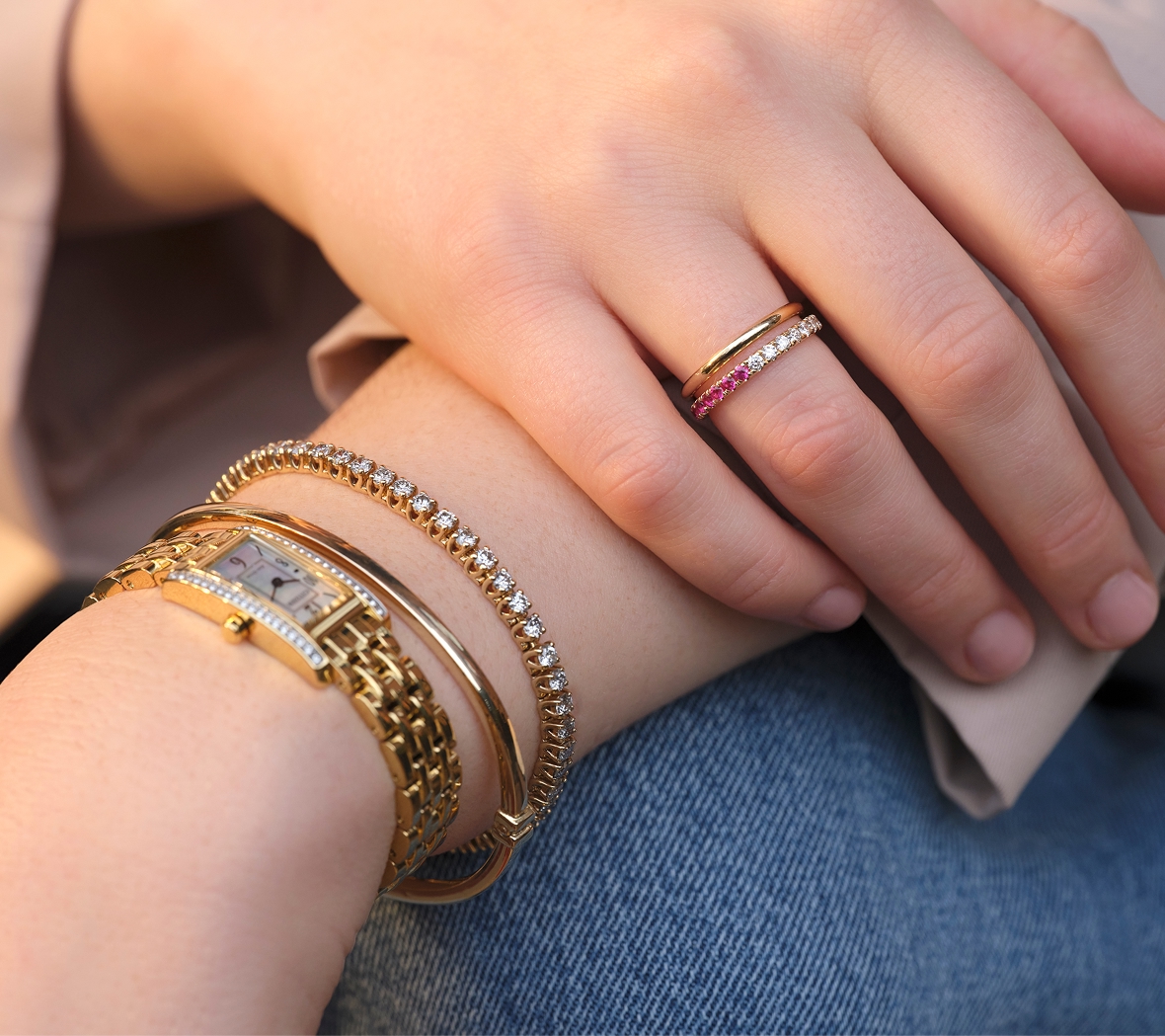 A yellow gold wrist stack featuring a watch, diamond tennis bracelet, and bangle. 