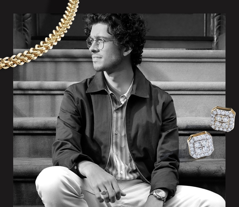 A black and white picture of a man sitting on a stoop wearing Helzberg jewelry. Over the image is a gold chain and a pair of men's diamond stud earrings.