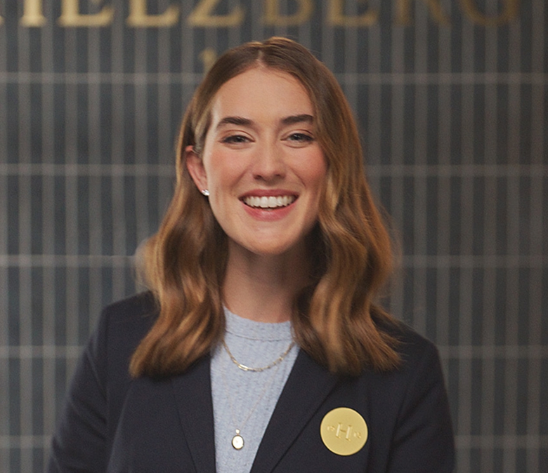 Helzberg jewelry expert standing at a counter wearing a dark blazer with a round gold pin.