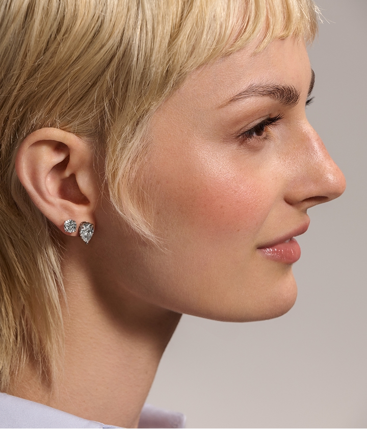 wo diamond solitaire studs featured on the ear of a woman's side profile.