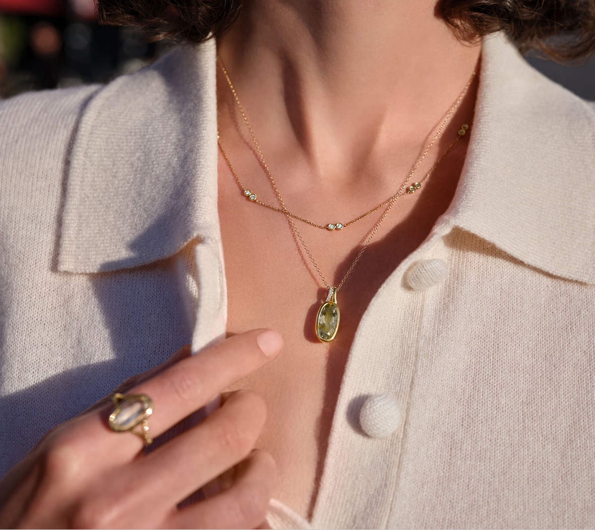 A woman wearing a green amethyst ring and a green amethyst necklaces
