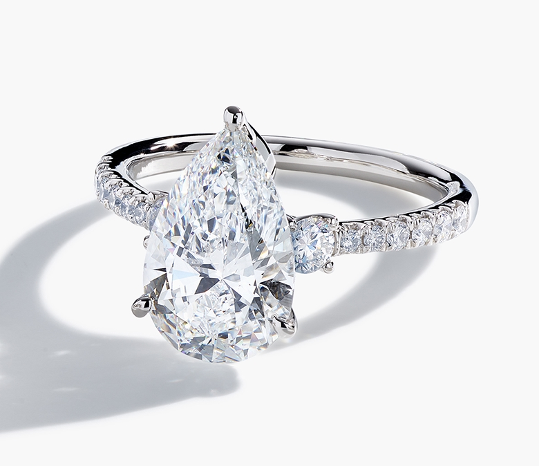 A white gold engagement ring featuring a pear-shaped diamond center stone with round diamond accents along the band.