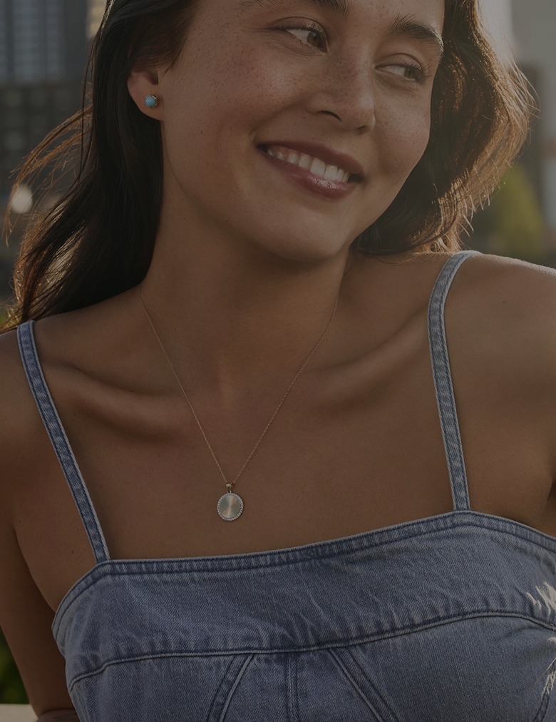Image of a woman outside infront of a city scape wearing Helzberg Jewelry. Clearance up to 50% off.